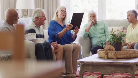 senior caucasian female therapist making notes, talking with diverse senior friends, slow motion