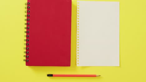 Video-of-notebook,-empty-sheet-with-copy-space-and-pencil-on-yellow-background