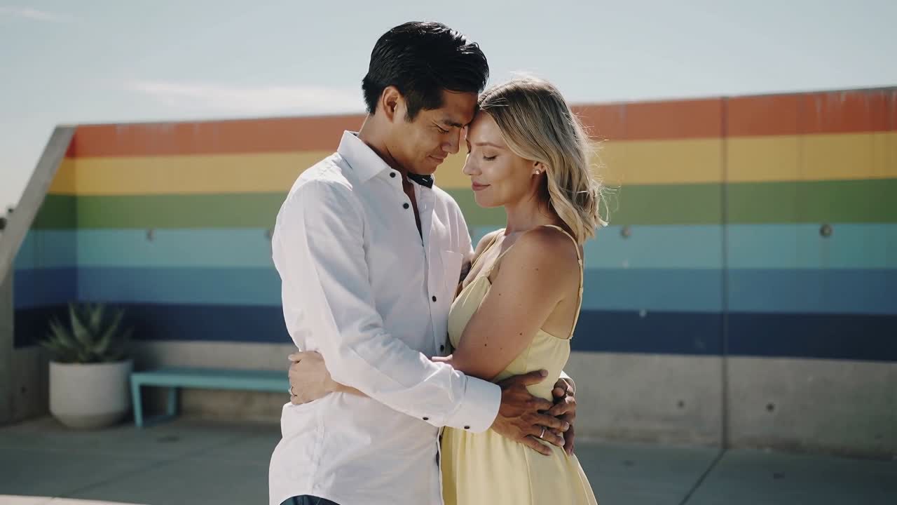 Pair making eye contact leaning heads showing love on rainbow wall hearts orbiting pair for ads