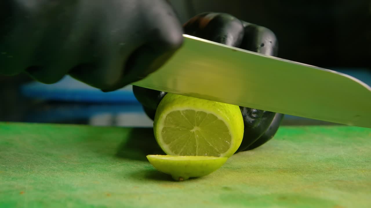 Chef slices off end of lemon into rounds on green plastic cutting board