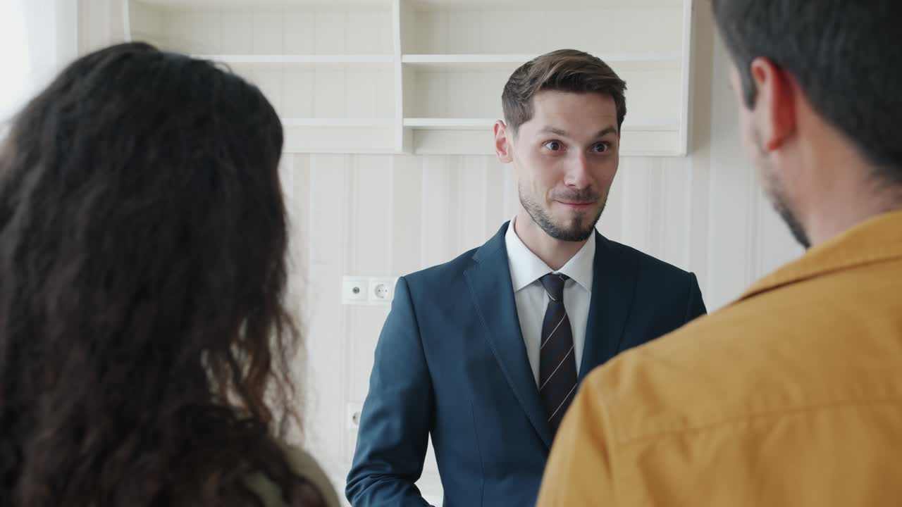 Portrait of real estate agent talking to customers indoors in new house smiling