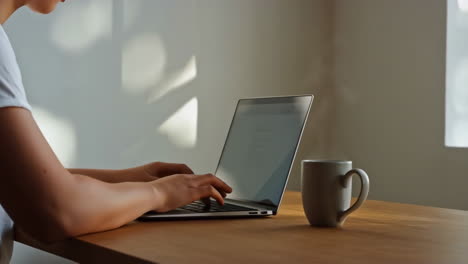 working on a laptop with a mug on the desk