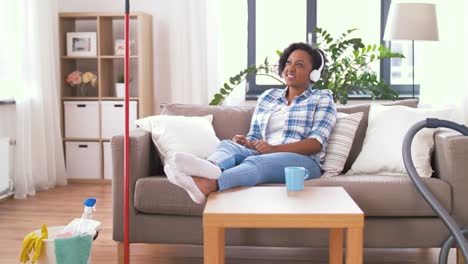 woman in headphones resting after home cleaning