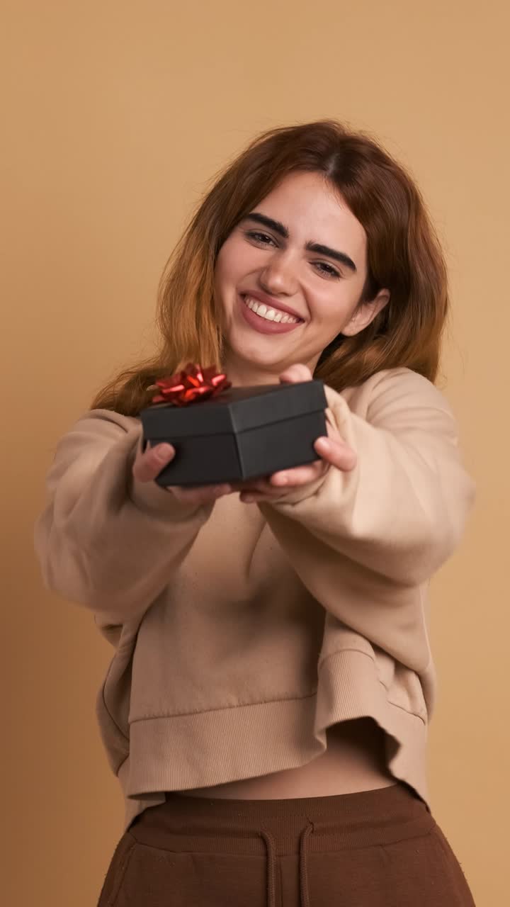 Cheerful young blond woman presenting gift box. Vertical Footage