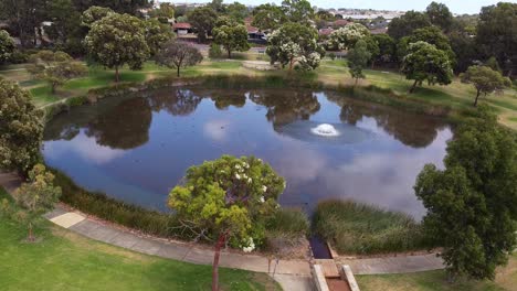 aerial reveal of circular lake with rainwater spillway - perth, australia