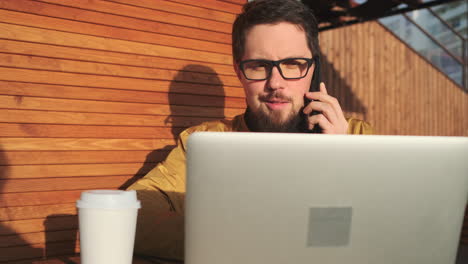 hombre trabajando al aire libre en una computadora portátil y hablando por teléfono