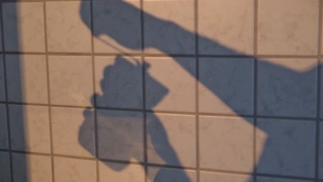 pared de azulejos de cocina con sombra de un hombre usando un molinillo de café manual tradicional