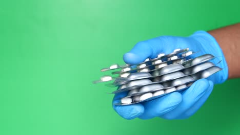 mano con guantes azules sosteniendo varios envases de pastillas
