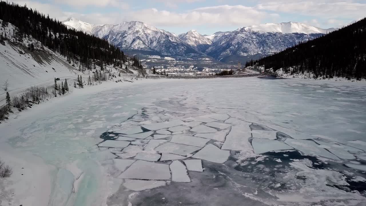 Rising above the beautiful frozen lake of the Spray Lakes Reservoir in Canada - aerial rising