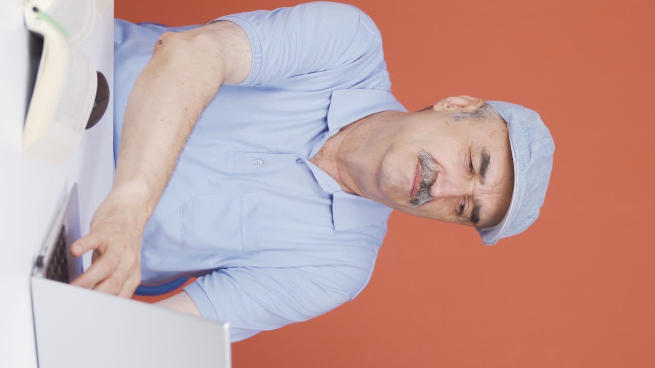Vertical video of The old man who can't use the application on the laptop.