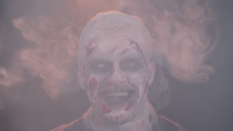 Zombie-Mann-Mit-Make-up,-Wunden,-Narben-Und-Weißen-Kontaktlinsen-Bläst-Rauch-Aus-Nase-Und-Mund