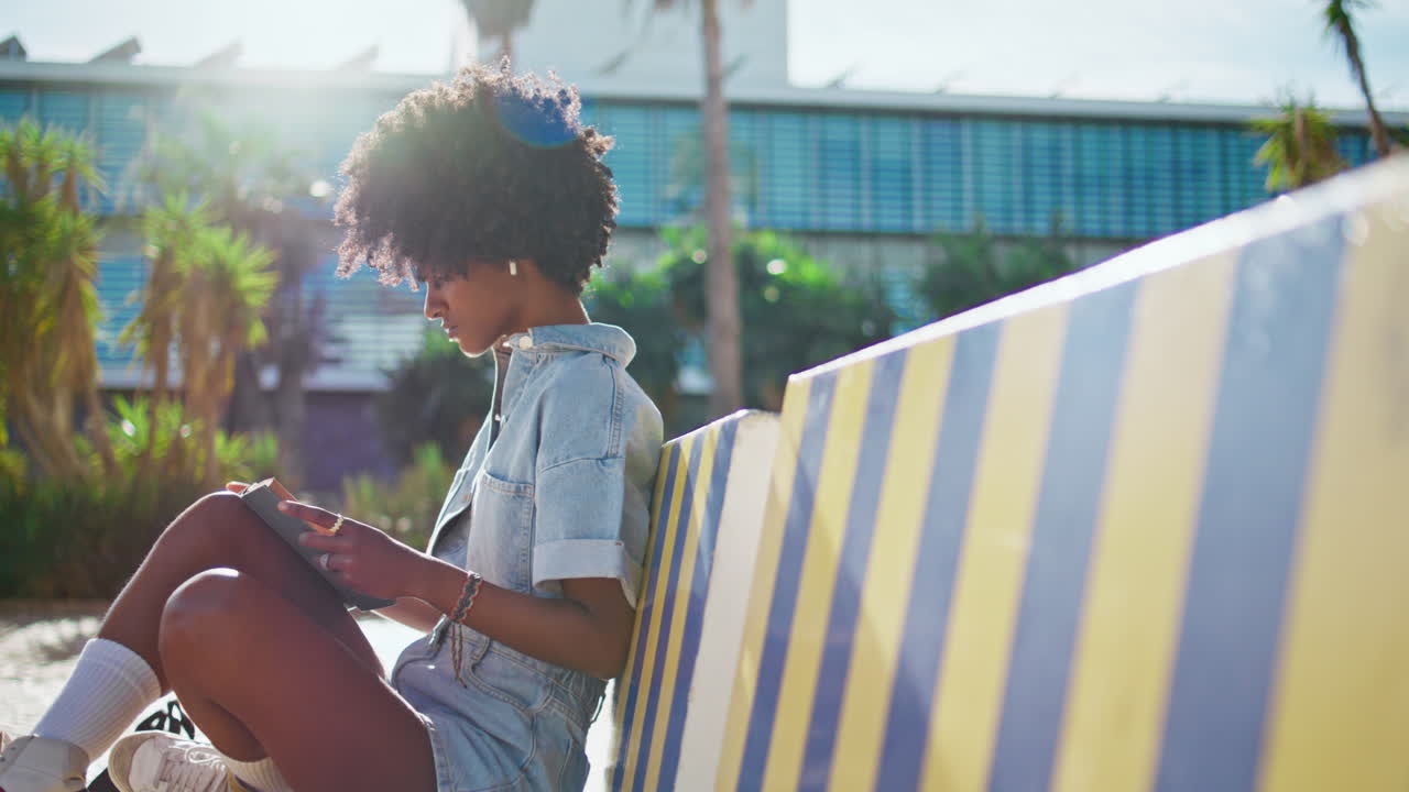 Relaxed student reading book sitting bench sunny street.  girl learning