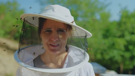woman beekeeper in protective gear surrounded by bees