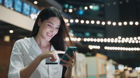 woman using mobile payment at night market