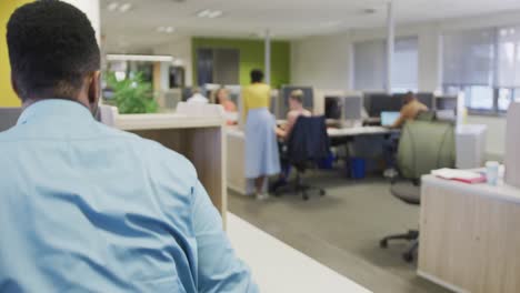 African-american-businessman-walking-with-documents-in-office