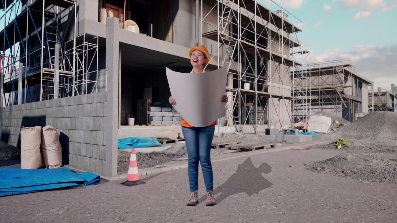 Ingeniera asiática con casco de seguridad mirando un plano que tiene en las manos y observando su entorno mientras está de pie en una obra en construcción para una nueva casa