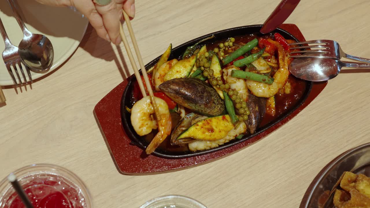 persona que come un plato de mariscos fritos