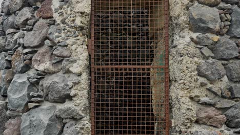 torre de edificio viejo abandonado con puerta de rejilla metálica oxidada, inclinada hacia arriba, exterior