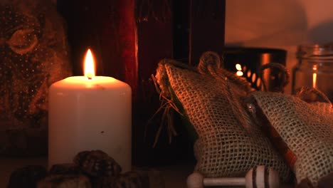 relaxing background detail shot of an herbal tea shop, with candles with flickering flames, herbs, books, small bags, jars, and some dust flying around