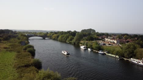 a river boat travelling along the river trent towards a road bridge and passing some moored boats