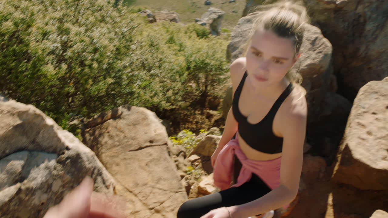 pareja cogida de la mano hombre ayudando a su novia escalada de montaña senderismo disfrutando de viajes al aire libre aventura pov