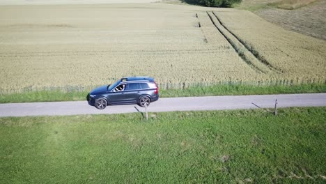 ein volvo-auto fährt in der nähe von feldern in der schweizer landschaft, waadt, drohnenansicht