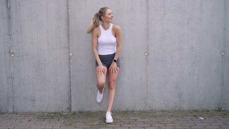 woman in workout clothes by a concrete wall