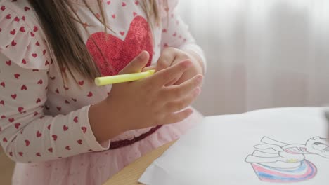 young girl sitting at a table, drawing with colorful crayons. ideal for themes of creativity, childhood development, learning, and art activities in a cozy indoor setting.