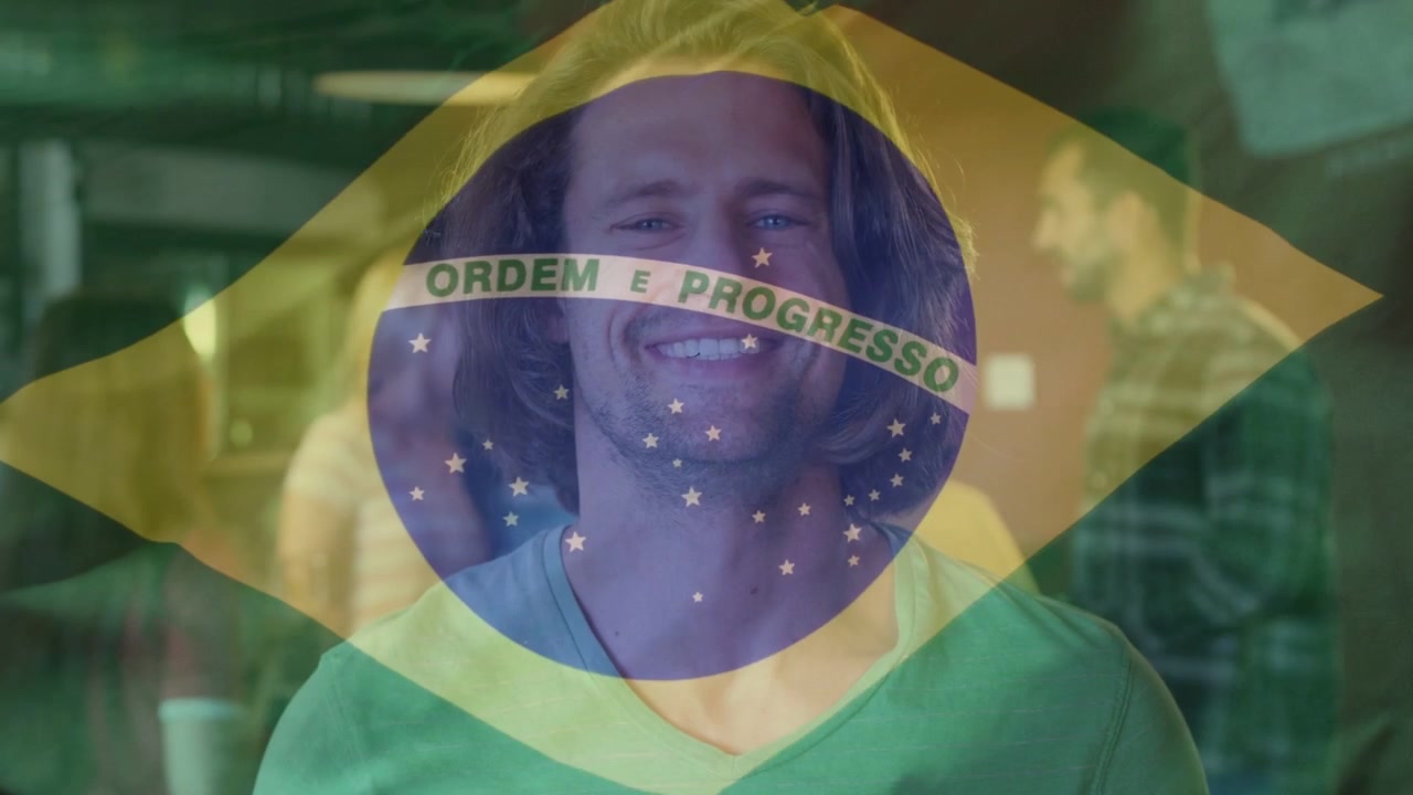 Homem olhando para a câmera, levantando garrafa verde e começando a bebericar, sorrindo, bandeira do Brasil sobrepondo o rosto.