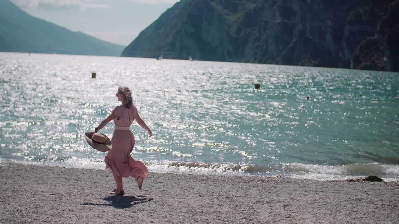 Woman Enjoys Scenic Beach Walk with Mountains