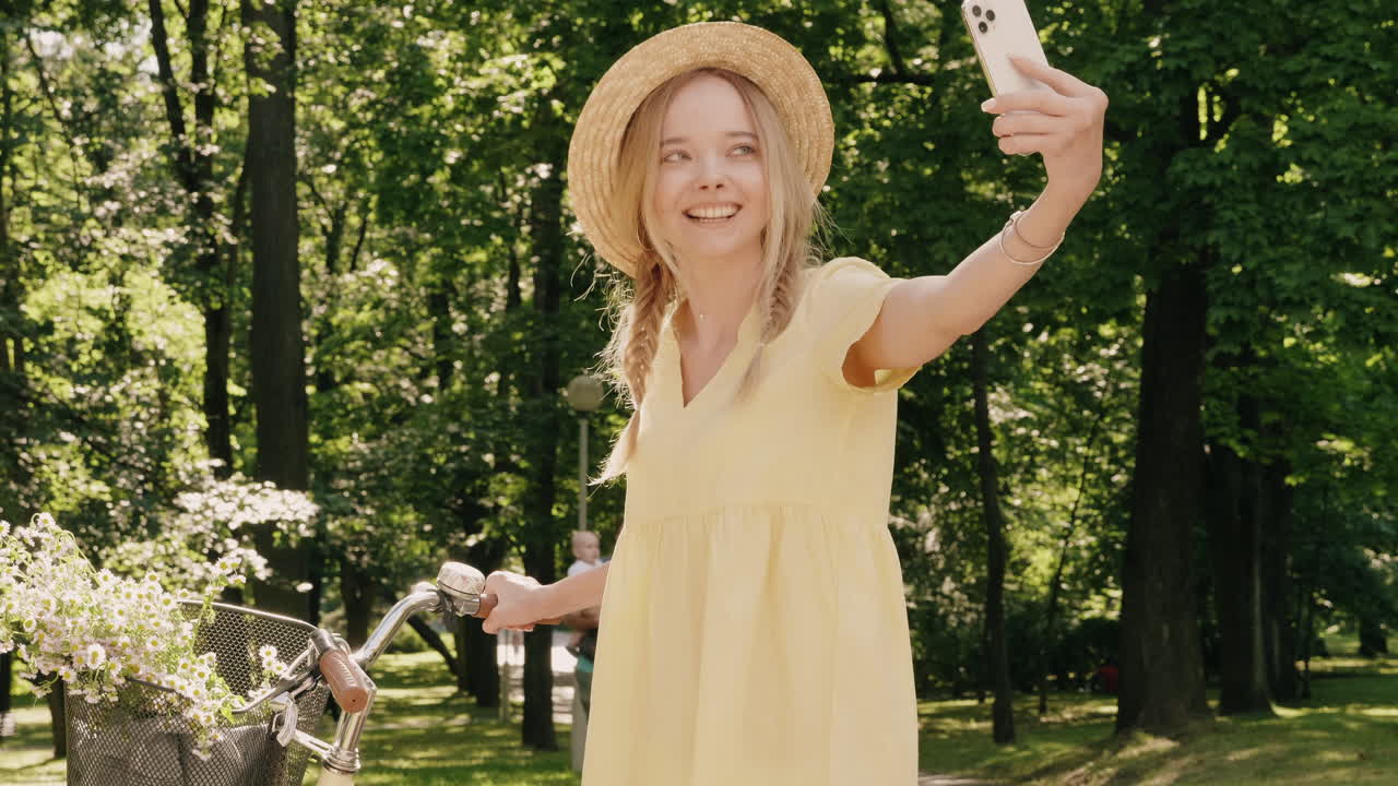 счастливая женщина делает селфи в парке на велосипеде.