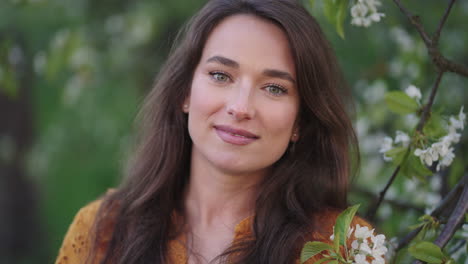 attractive-young-woman-in-blooming-orchard-in-spring-day-portrait-shot-charming-smile-and-green-eyes