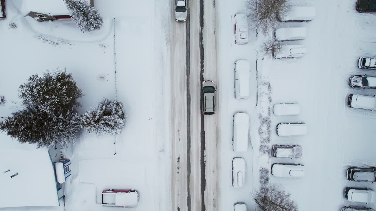 A center frame overhead of the main road through Breckenridge in winter, as cars drive through snow and traffic into the popular Colorado mountain town for a ski vacation at the world famous resort.