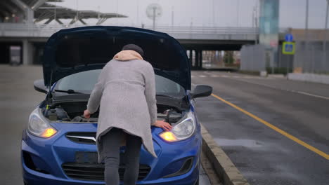 una mujer arreglando un coche averiado.