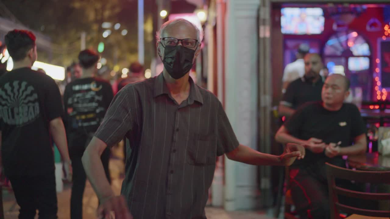 Malaysian old man vibing at loud music from nightclubs in Kuala Lumpur, Malaysia.