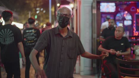 malaysian old man vibing at loud music from nightclubs in kuala lumpur, malaysia.