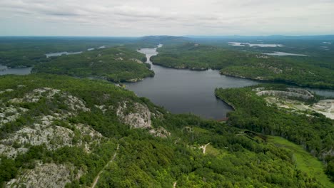 Vista-Aérea-De-Un-Lago-Natural-Entre-Un-Bosque-Rocoso-Y-Montañoso.