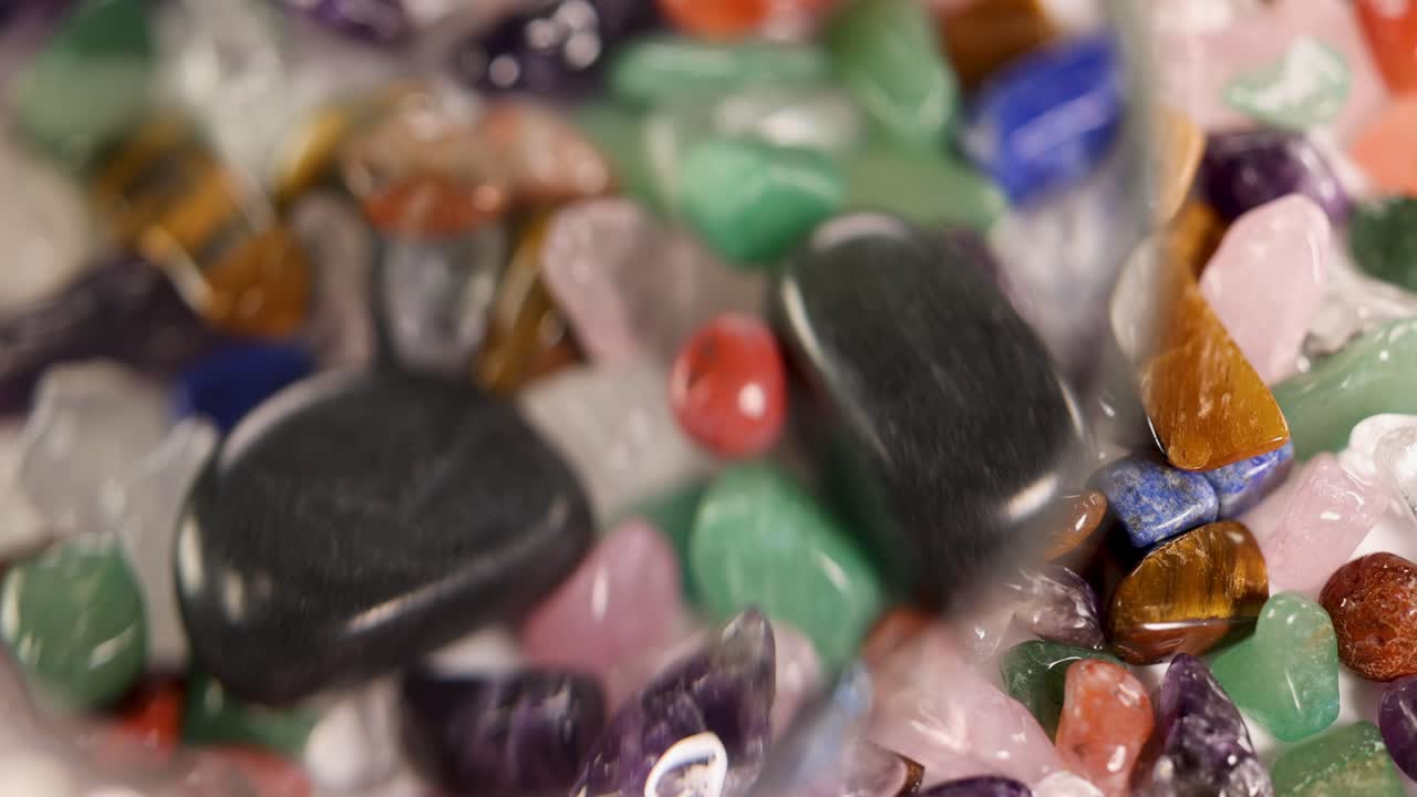 A magnifying glass reveals vibrant chakra stones, enhancing their colors and textures under warm lighting
