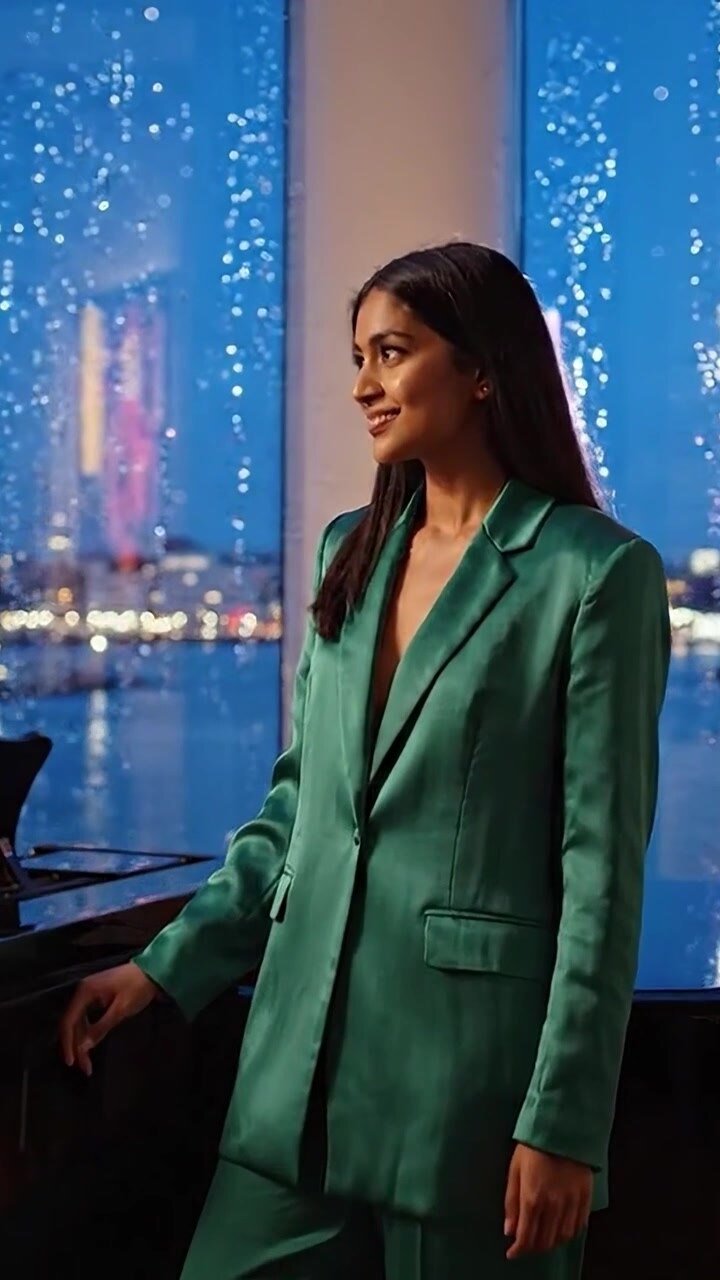 Elegant pianist i stilig grønn dress ser tankefullt mens hun er omgitt av naturskjønne bylys og regndråper, noe som skaper en fengslende og kunstnerisk atmosfære