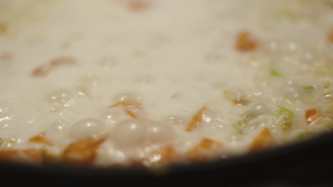 las burbujas salen cuando el guiso de verdura lechosa hierve de cerca.