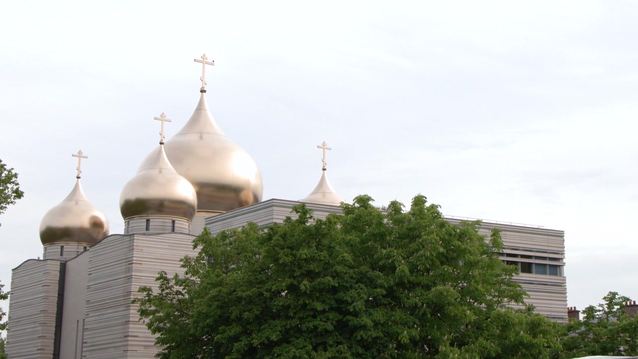 Statisk mellembillede af gyldne løgkupler oven på en moderne ortodoks katedral i Paris.