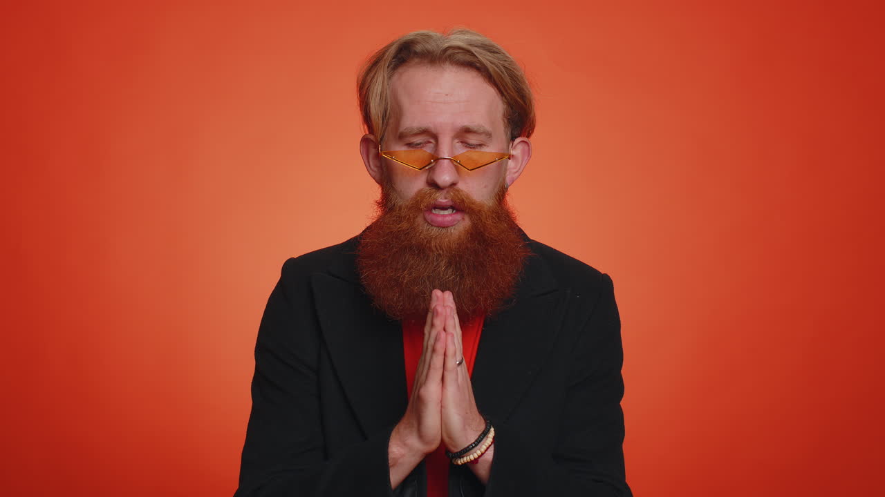 Trendy young adult man praying, looking upward and making wish, asking God for help, begging apology