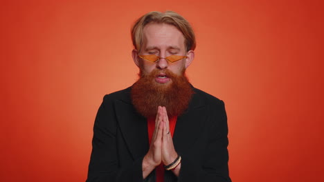 trendy young adult man praying, looking upward and making wish, asking god for help, begging apology