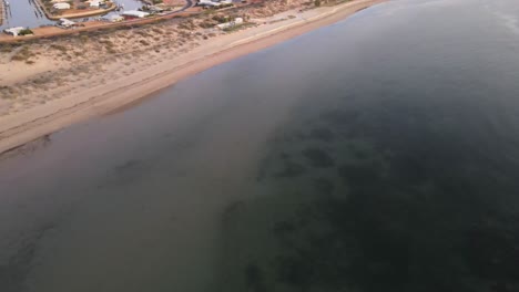 Drone-aerial-panning-up-slowly-over-the-ocean-during-sunrise-over-Exmouth-beach