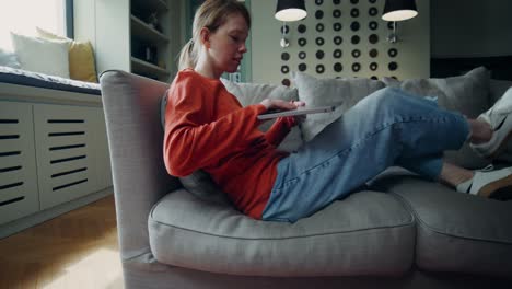 woman using tablet/laptop on a sofa