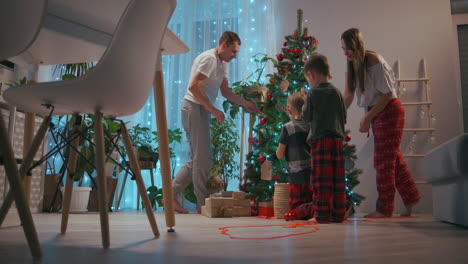 The-family-decorates-the-Christmas-tree-together.-The-father-is-a-mother-and-two-children-put-on-Christmas-trees-together.-Happy-family-on-Christmas-Eve.-High-quality-4k-footage