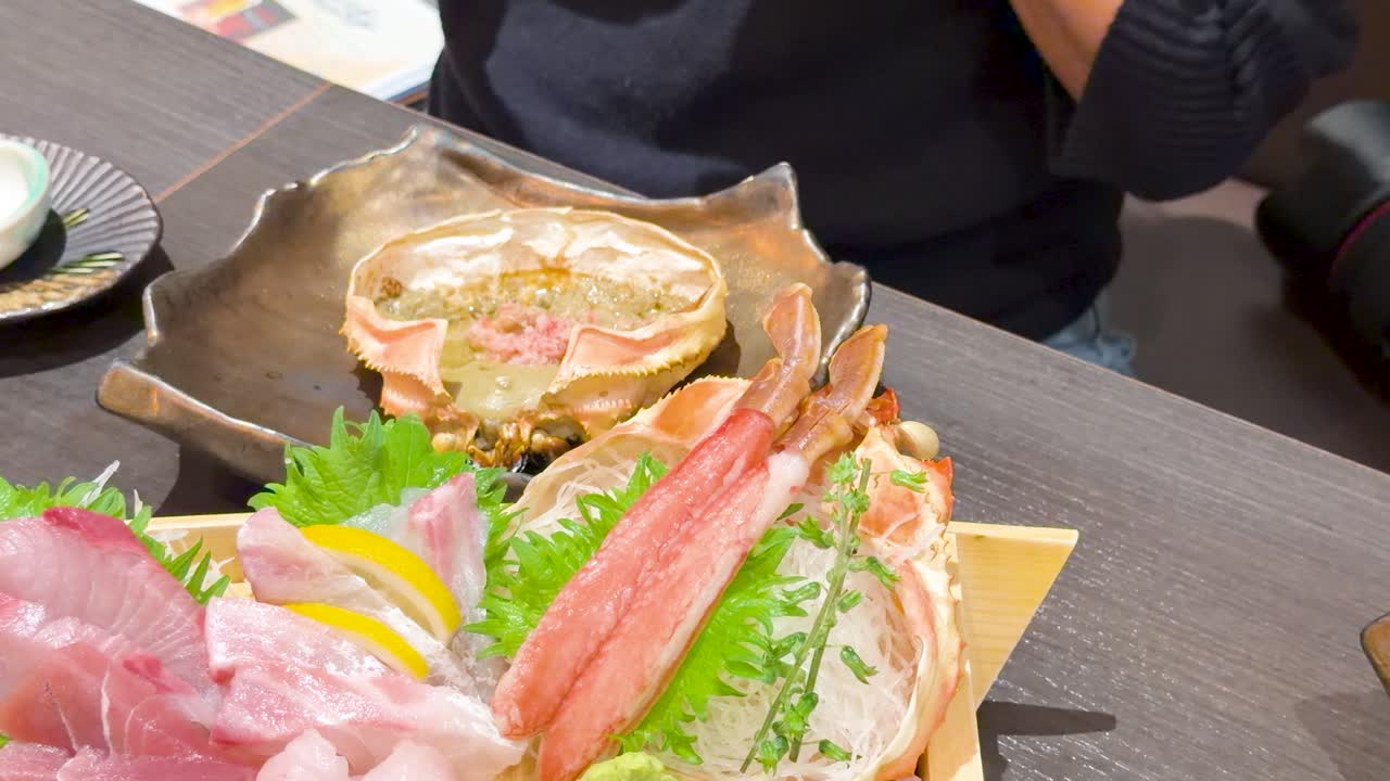 東京で、新鮮な刺身とカニ味噌を食べる準備をしている人物のクローズアップショット。