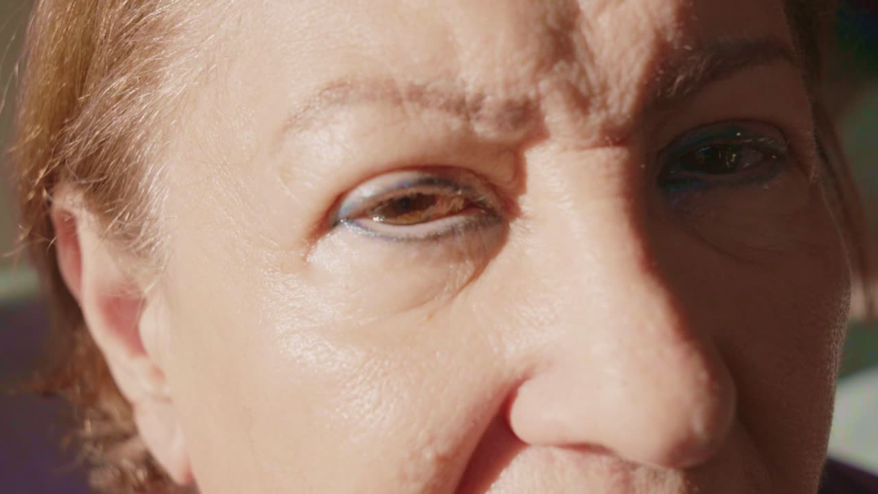 Stijgende schuifopname, serieuze oudere vrouw met bloeddoorlopen ogen door natuurlijke veroudering, latijns-amerikaanse oma geeft om