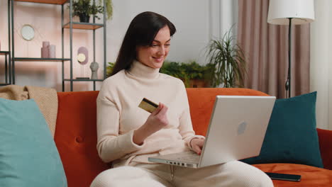 Young-woman-girl-using-credit-bank-card-and-laptop,-transferring-money,-purchases-online-shopping