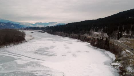 Frozen-North-Thompson-River,-Snow-Covered-Mountains,-and-Pine-and-Spruce-Tree-Forests-in-BC,-Canada-Along-Yellowhead-Highway-5-in-Winter---Aerial-Flight